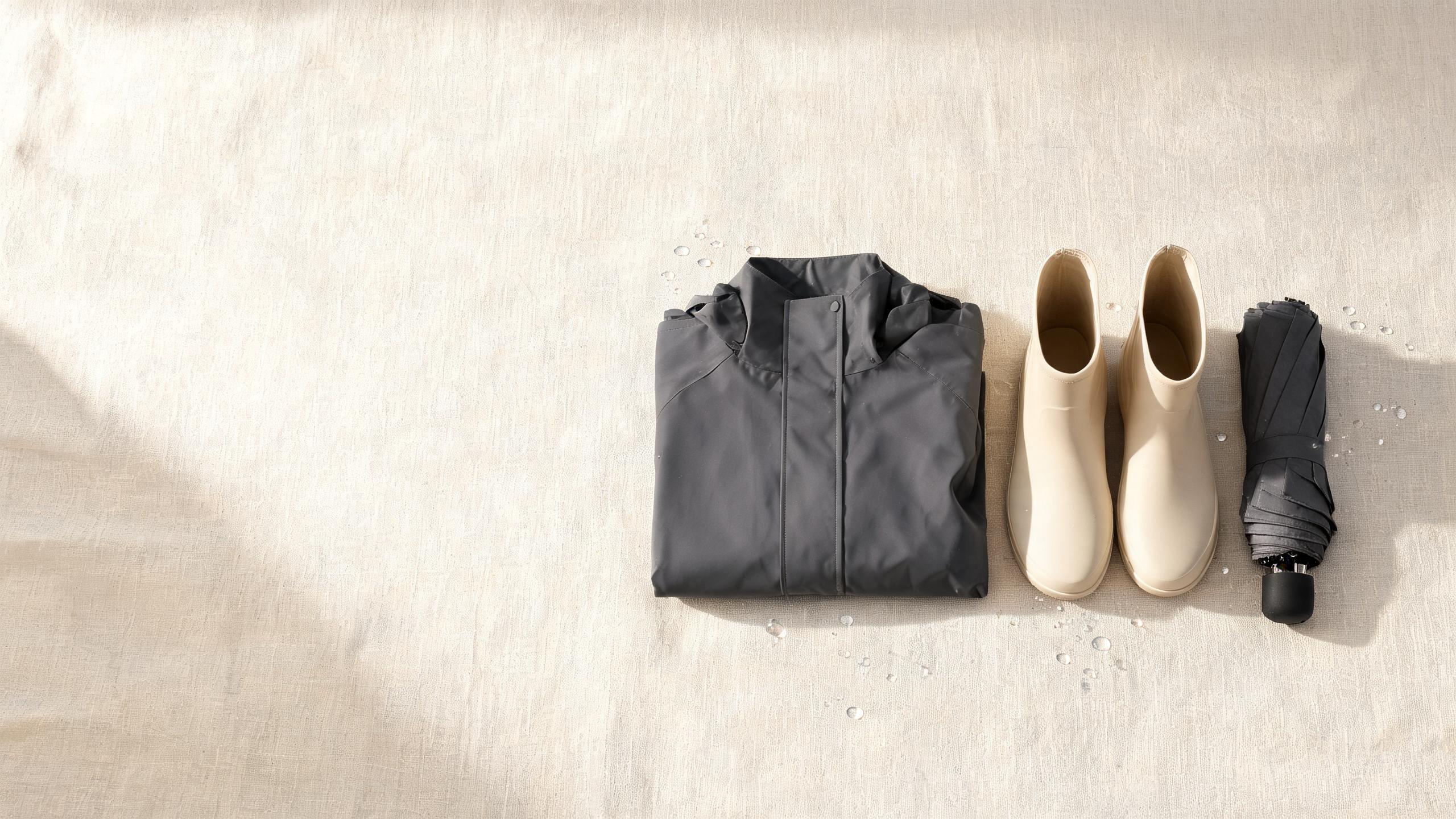 Solen Unity rainwear flat lay - a folded waterproof raincoat, rain boots and a long umbrella